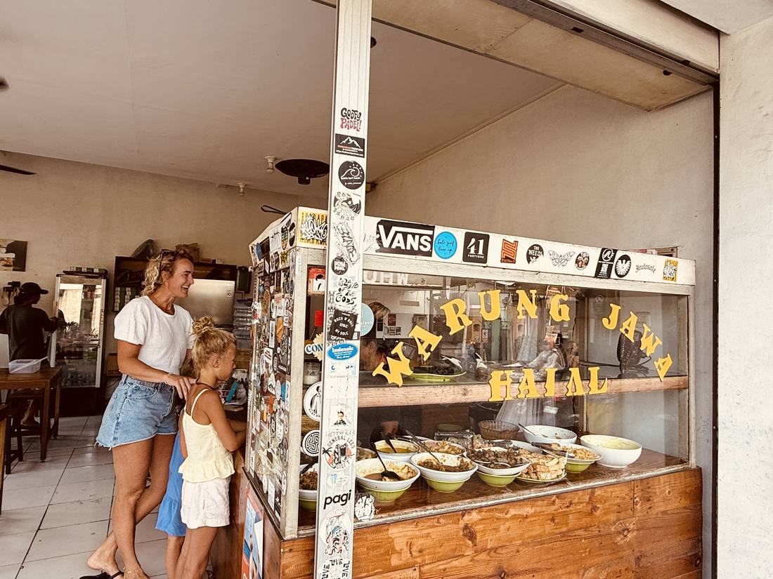 Ilse met haar dochter bij een warung waar het eten in schalen klaarstaat