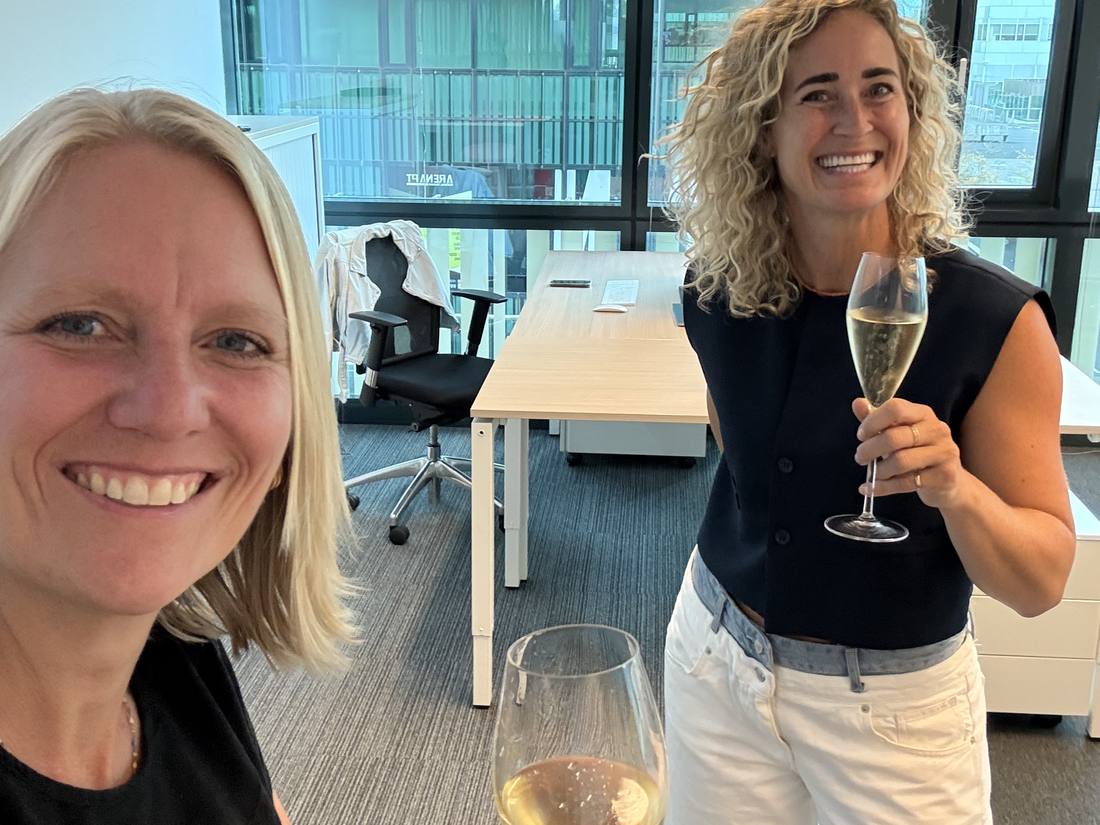 Nynke en Ilse proosten met een glas bubbels op hun kantoor in Amsterdam Zuidoost