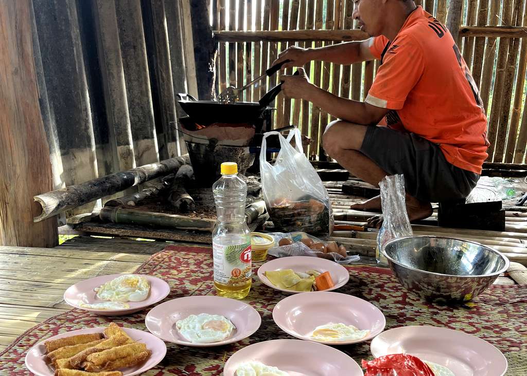 De gastvrouw bakt eieren bij een homestay in een bergdorp bij Chiang Mai, Noord-Thailand