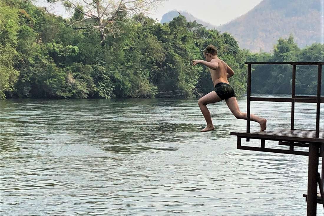 Een jongen springt van het platform de River Kwai in, Thailand