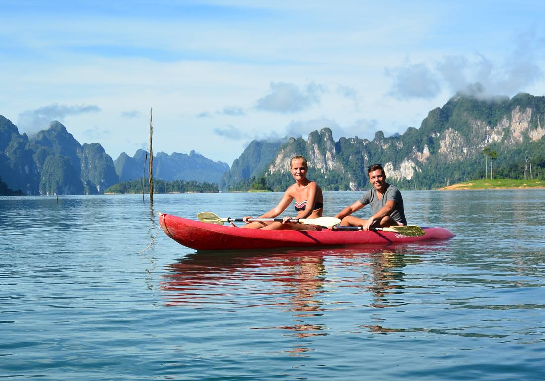 Twee reizigers in een rode kajak op het meer van Khao Sok, met de kalkrotsen erachter, Thailand