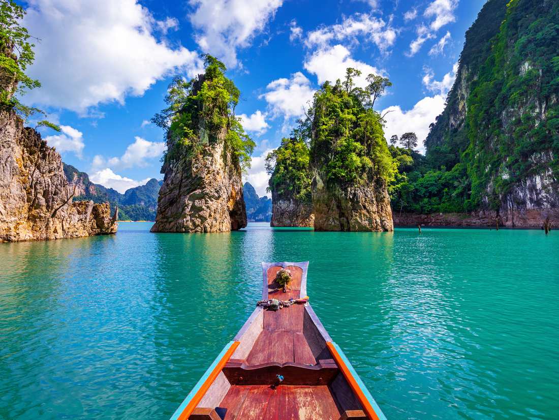 Longtailboot tussen de kalkrotsen op het meer van Khao Sok, Zuid-Thailand