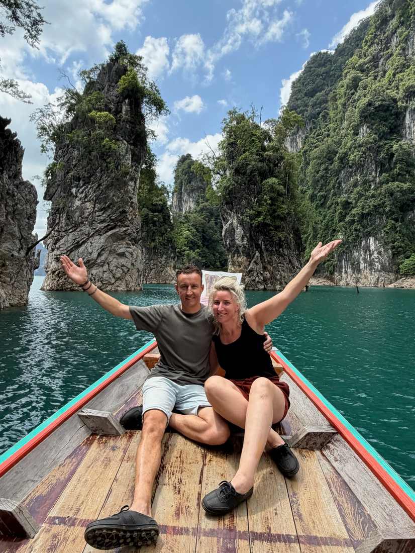 Stel met de armen omhoog in een longtailboot op het meer van Khao Sok, Zuid-Thailand