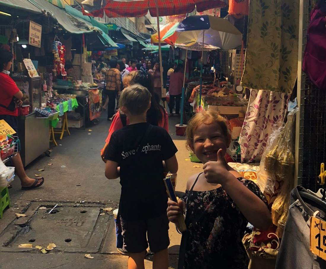Een kind kijkt rond tussen de kraampjes op een avondmarkt in Thailand