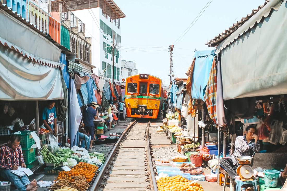 De trein rijdt dwars door de kraampjes van de Maeklong-treinmarkt bij Bangkok, Thailand