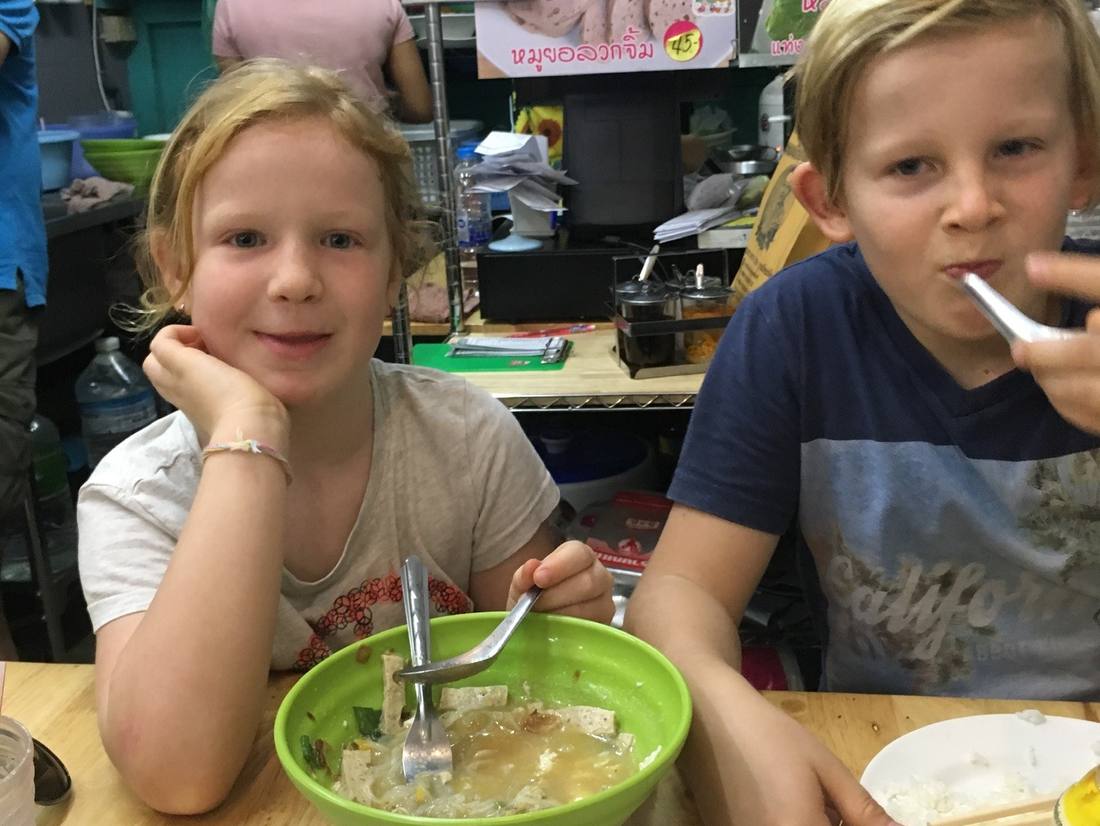 Twee kinderen eten noedelsoep in een klein eettentje in Thailand
