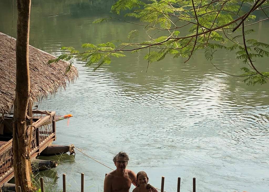 Reiziger kijkt uit over de rivier de Kwai vanaf een vlonder, Thailand