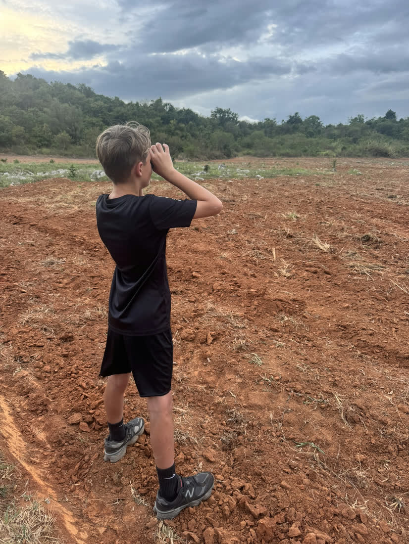 Kind speurt met een verrekijker het platteland van Thailand af