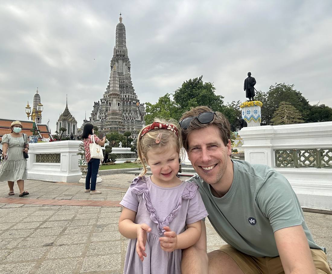 Vader met zijn dochtertje voor de tempel Wat Arun in Bangkok, Thailand