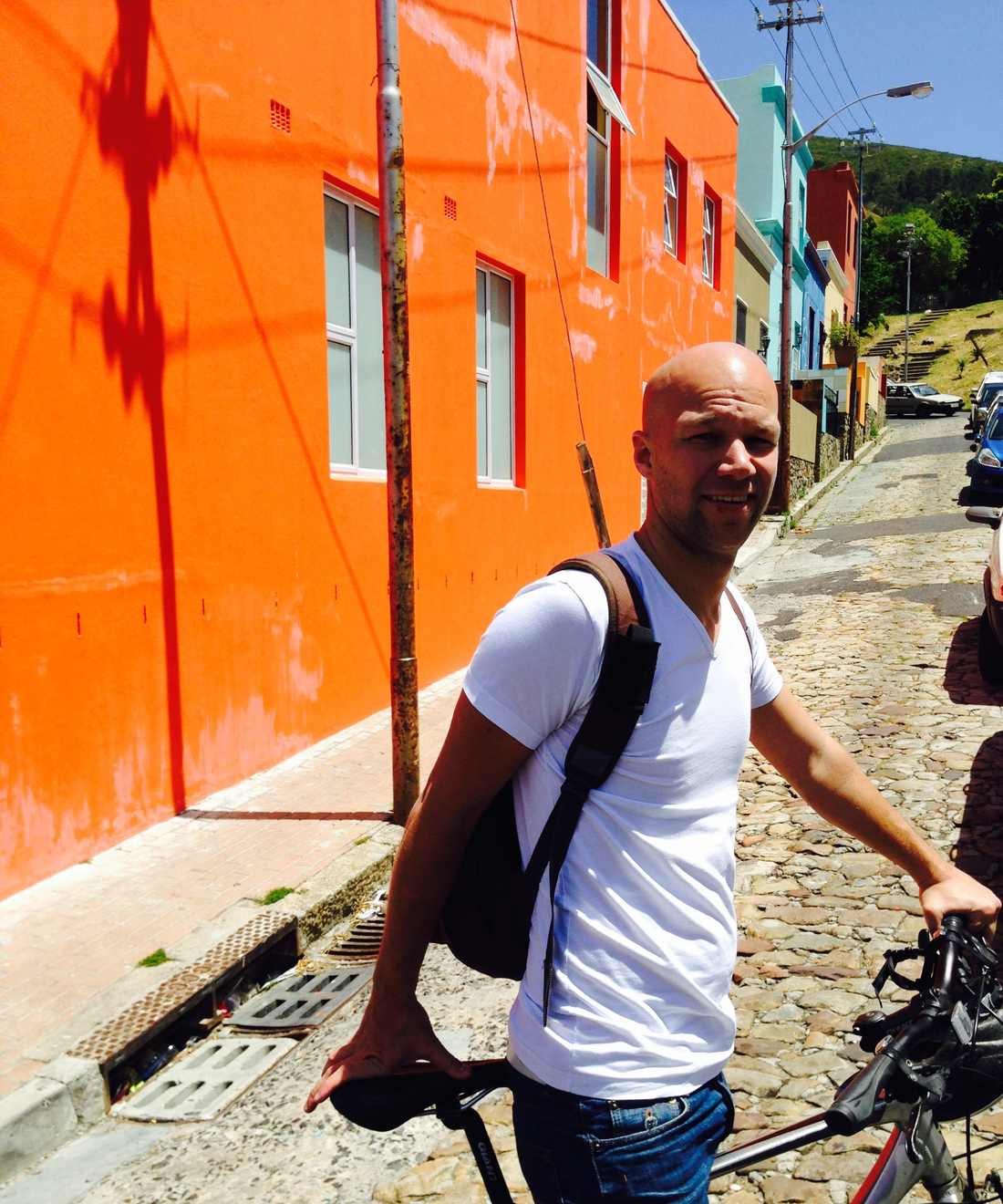 Met de fiets door de Bo-Kaap in Kaapstad, langs een knaloranje huis, Zuid-Afrika