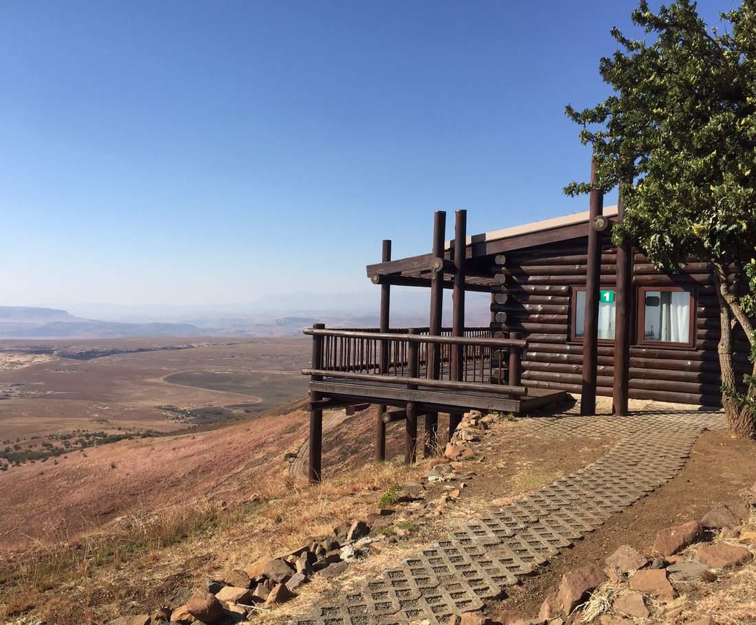 Een houten huisje op de bergrand met uitzicht over de vlakte bij Golden Gate, Zuid-Afrika