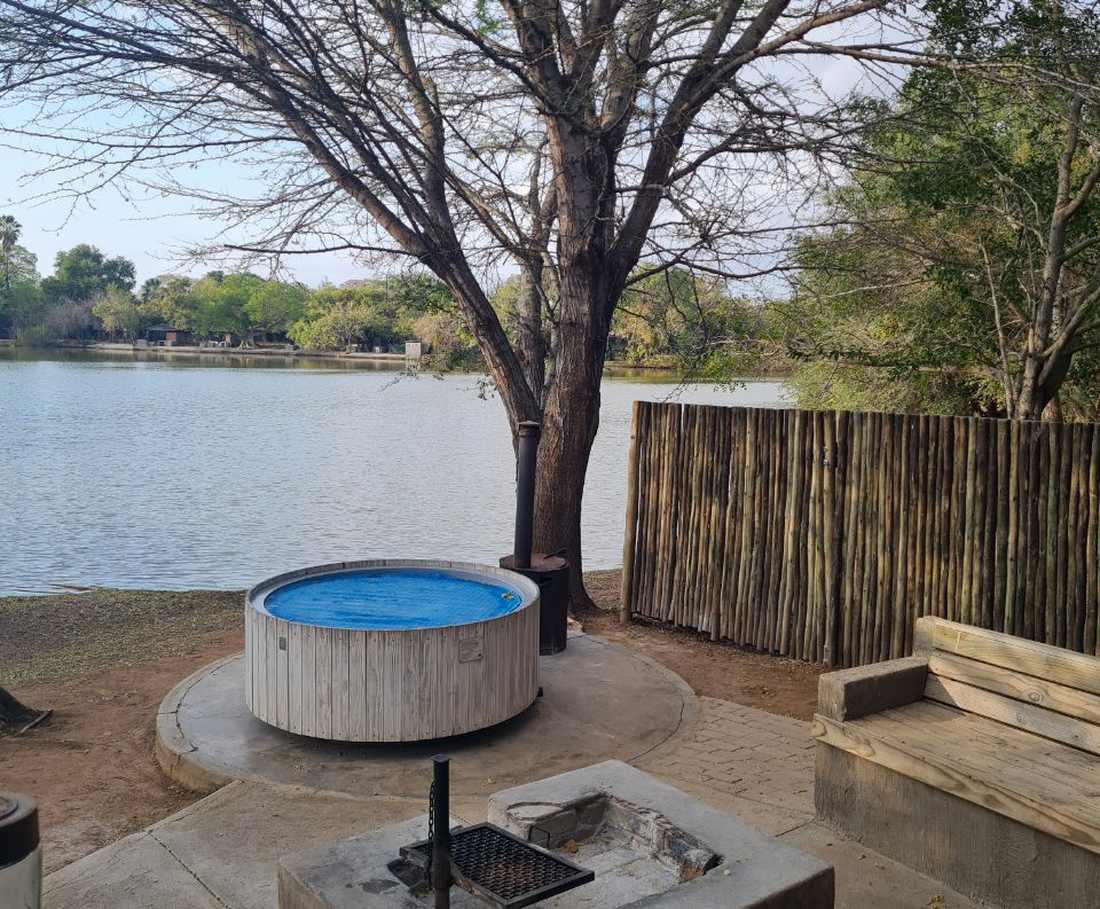 Een houtgestookte hottub naast de vuurplaats, met het water erachter, Zuid-Afrika