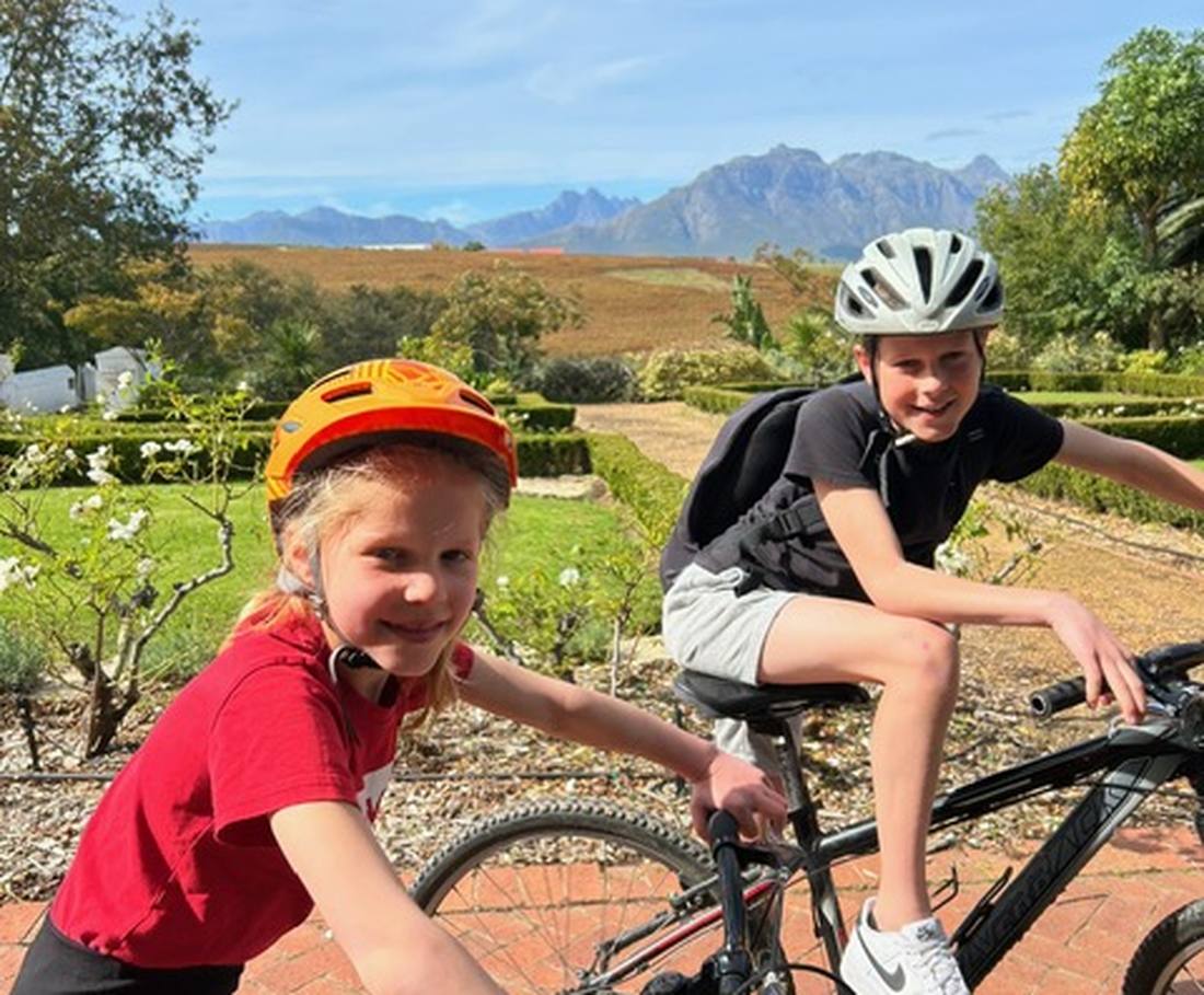 Twee kinderen mountainbiken door de wijnvelden bij Stellenbosch, Zuid-Afrika