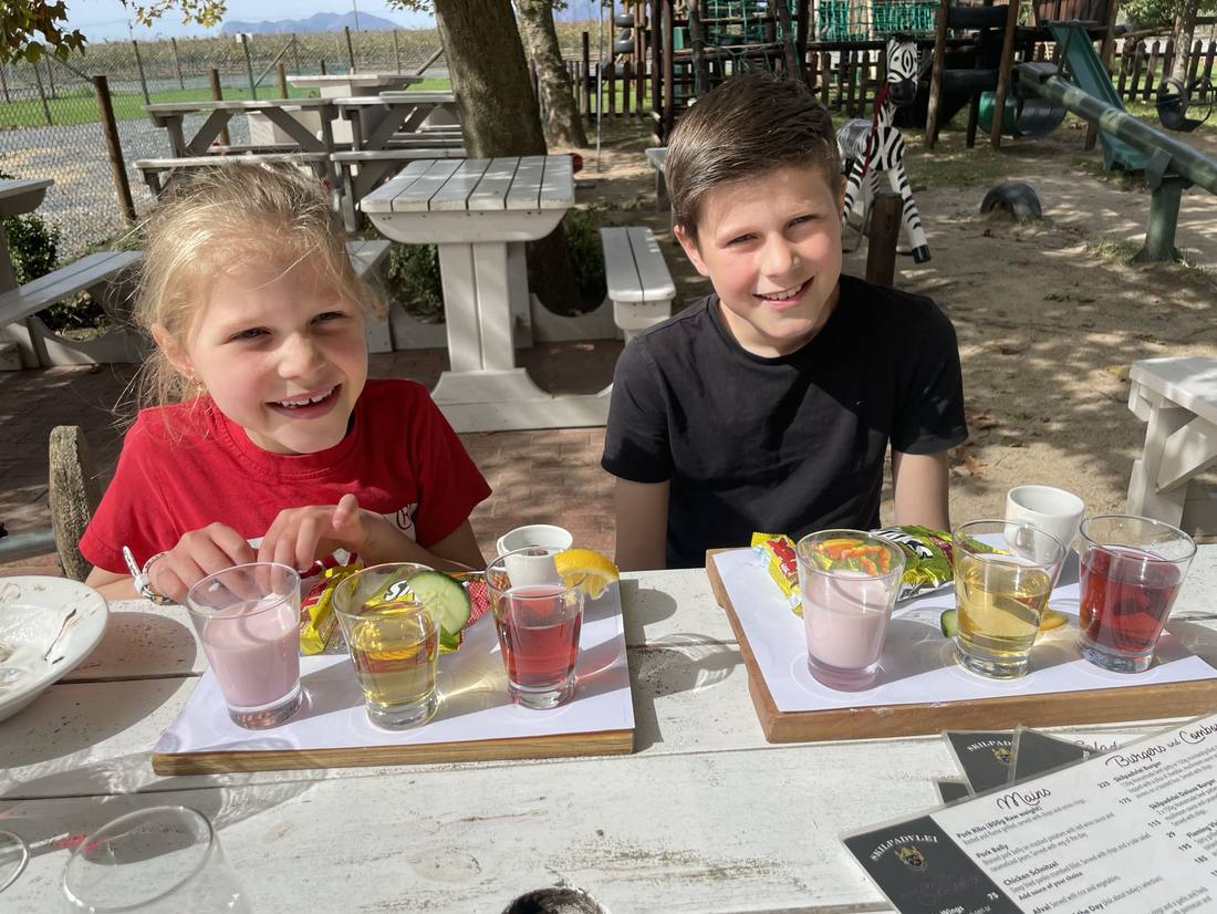 Kinderen met een mocktail aan tafel op safari, Zuid-Afrika