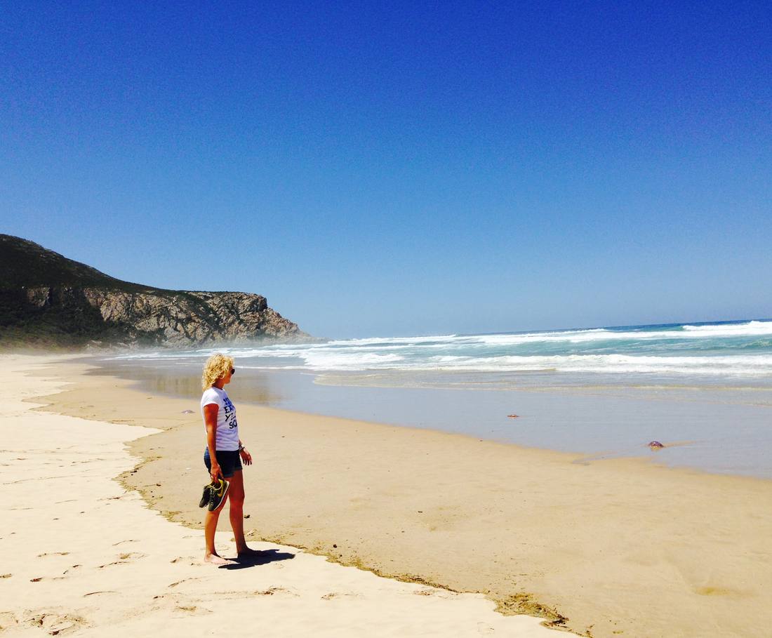 Een kind op het brede strand bij Plettenberg Bay, Zuid-Afrika