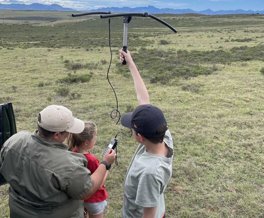 Een ranger zoekt met een antenne naar dieren, met kinderen erbij, Zuid-Afrika