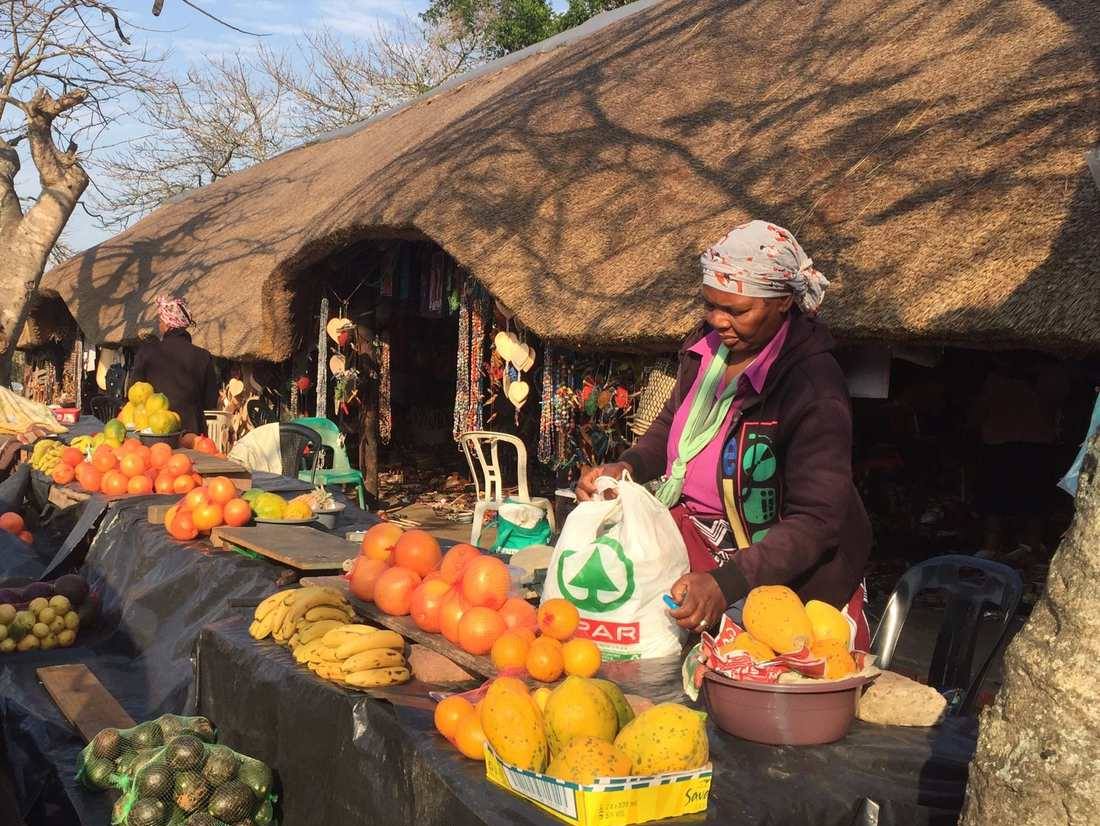 Een marktkraam met sinaasappels, bananen en mango's langs de weg bij St. Lucia, Zuid-Afrika
