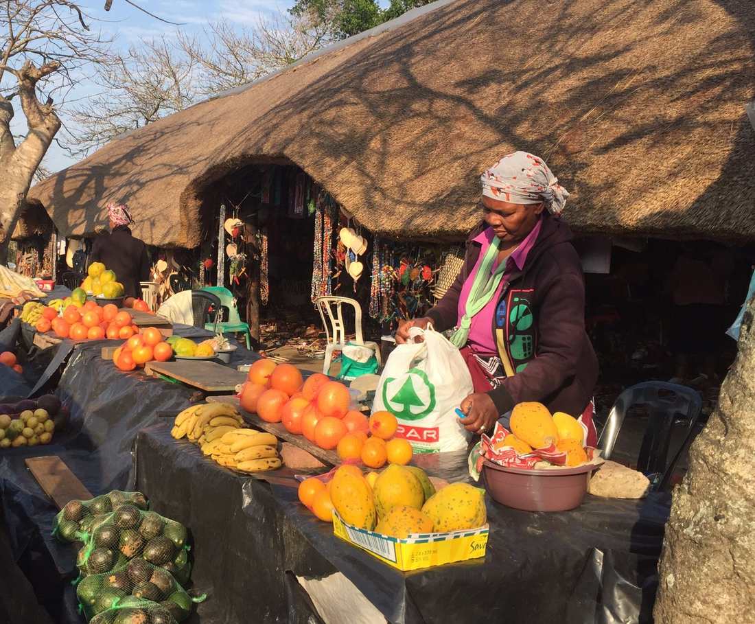 Een marktkraam met sinaasappels, bananen en mango's langs de weg bij St. Lucia, Zuid-Afrika