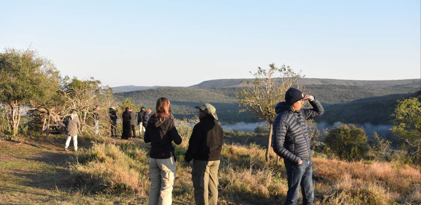Reizigers in dikke jassen kijken bij zonsondergang uit over het reservaat, Zuid-Afrika