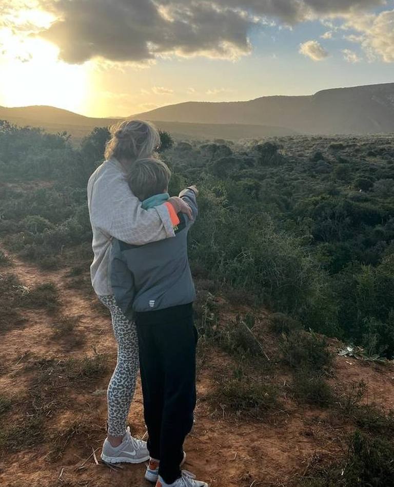 Twee reizigers kijken met een arm om elkaar heen uit over de heuvels bij zonsondergang, Zuid-Afrika