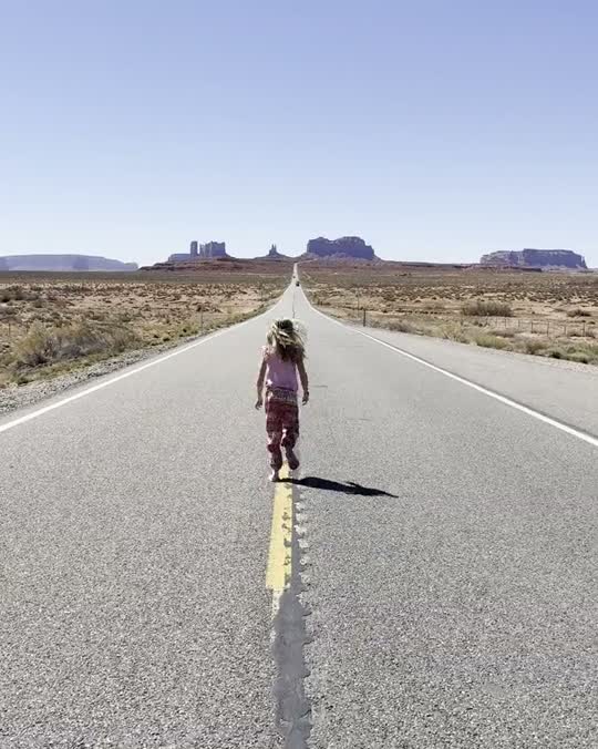 Kind rent over een lege weg richting Monument Valley