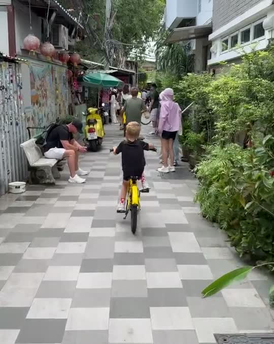 Kind op de fiets tussen de kraampjes in een drukke fietstocht-bangkok in Bangkok
