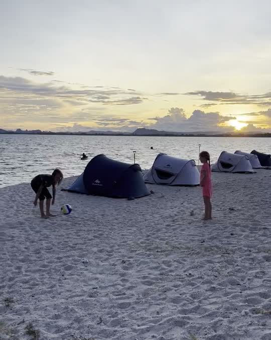 Kinderen bij tentjes op het strand bij zonsondergang in Thailand